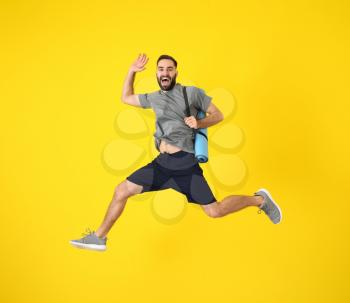 Young sporty man jumping against color background�