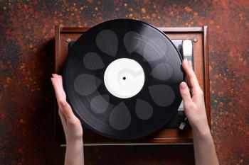 Female hands with vinyl disc and record player on grunge background�