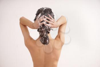 Young woman washing hair on white background�