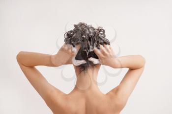Young woman washing hair on white background�