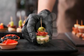 Chef preparing tasty canapes for serving, closeup�