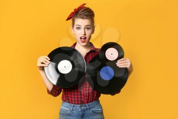 Beautiful pin-up woman with vinyl discs on color background�