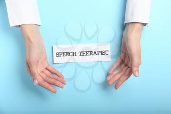 Doctor's hands and paper with text SPEECH THERAPIST on color background�