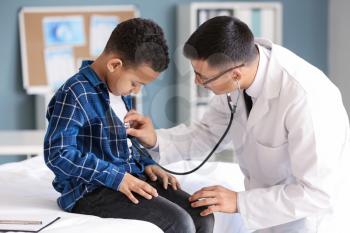 Pediatrician examining African-American boy in clinic�