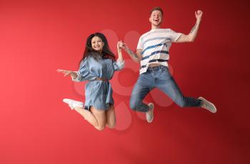 Happy jumping couple against color background�