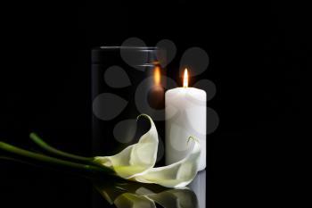Mortuary urn, burning candle and flowers on dark background�