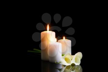 Burning candles and flowers on dark background�