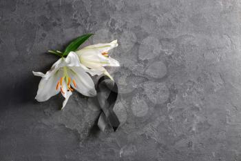 Black funeral ribbon and flowers on grey background�