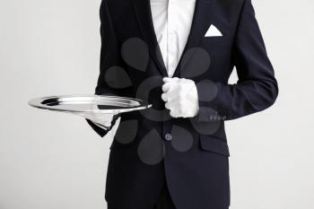 Waiter with empty tray on light background�