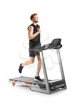 Sporty young man training on treadmill against white background�