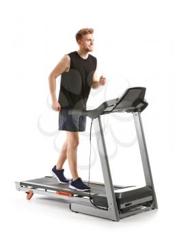 Sporty young man training on treadmill against white background�