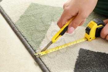 Woman with tape measure cutting carpet�