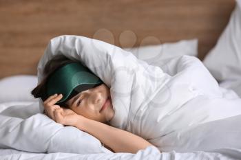 Sleepy young woman with mask in bed�