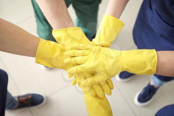 Team of janitors putting hands together�