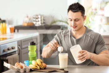 Sporty man making protein shake at home�