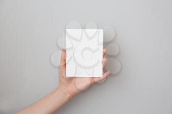 Female hand with blank invitation card on light background 
