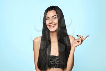 Portrait of beautiful young woman with healthy long hair on color background�