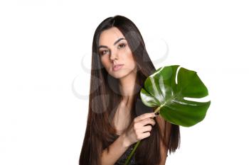 Portrait of beautiful young woman with healthy long hair holding tropical leaf on white background�