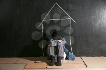 Homeless little girl sitting on floor near dark wall�
