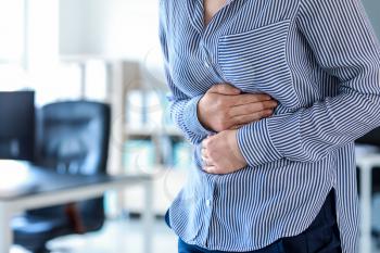 Young woman suffering from stomachache in office�