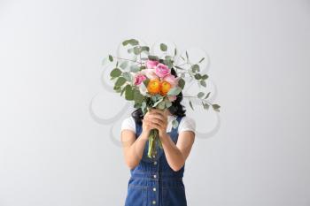 Portrait of beautiful woman with bouquet on light background�
