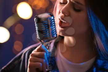 Beautiful female singer with microphone on stage, closeup�