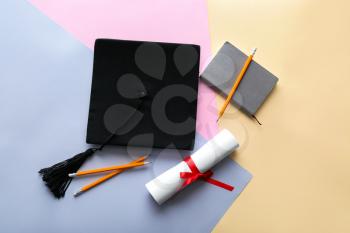 Mortar board with diploma and stationery on color background. Concept of high school graduation�