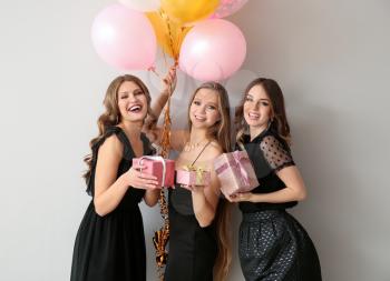 Beautiful young women with gifts and air balloons on light background�