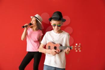 Little musicians playing against color background�