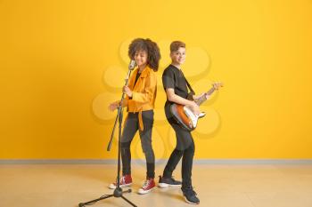Teenage musicians playing against color wall�