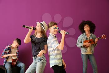 Teenage musicians playing against color background�
