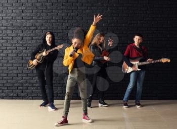 Band of teenage musicians playing against dark wall�