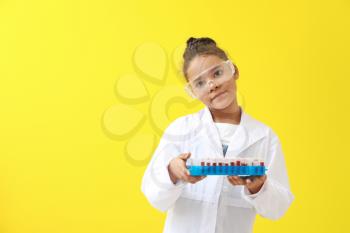 Little African-American laboratory assistant holding test tubes with blood samples on color background�