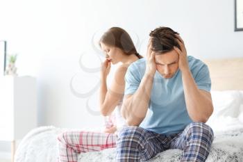 Upset young couple after quarrel sitting on bed�