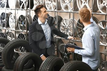 Seller helping man to choose disks and tires in car store�