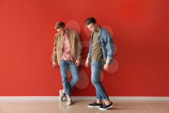 Fashionable young men near color wall�