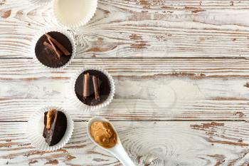 Tasty chocolate peanut butter cups on white wooden table�