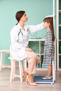 Female doctor measuring height of little girl in hospital�