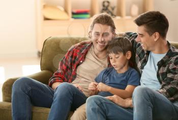 Happy gay couple with adopted child at home�