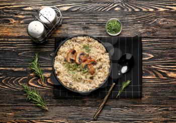 Frying pan with tasty risotto on wooden table�