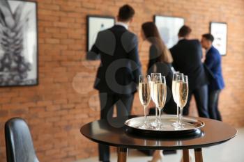 Glasses of champagne on table in art gallery�