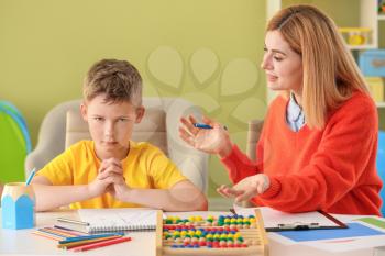 Female psychologist working with boy suffering from autistic disorder�