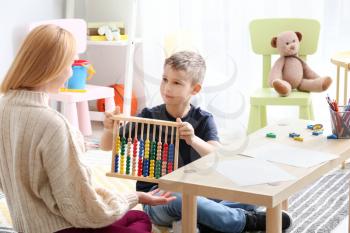 Female psychologist working with boy suffering from autistic disorder 