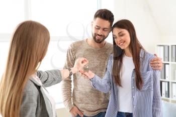 Real estate agent giving a keys from new house to young couple�