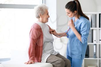 Medical worker examining senior woman in nursing home�