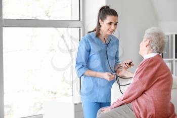 Medical worker examining senior woman in nursing home�