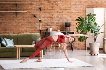 Young woman practicing yoga at home�