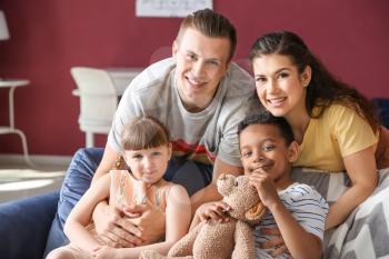 Happy couple with adopted children at home�