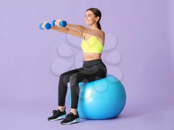 Young sporty woman doing exercises with fitball on color background�