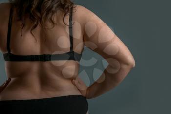Beautiful plus size woman on grey background, back view. Concept of body positive�